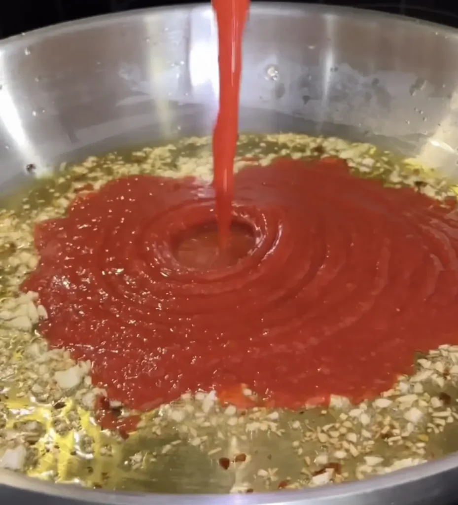 Adding the tomato sauce on the pan