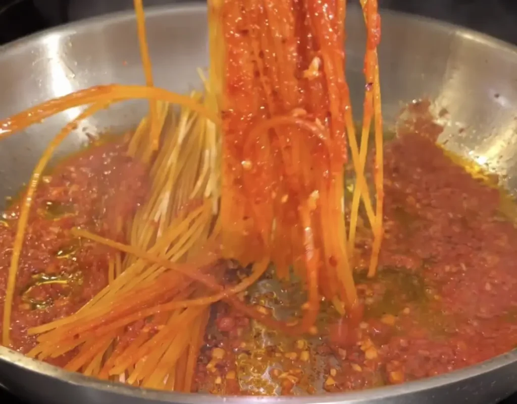 Adding the spaghetti to the pan