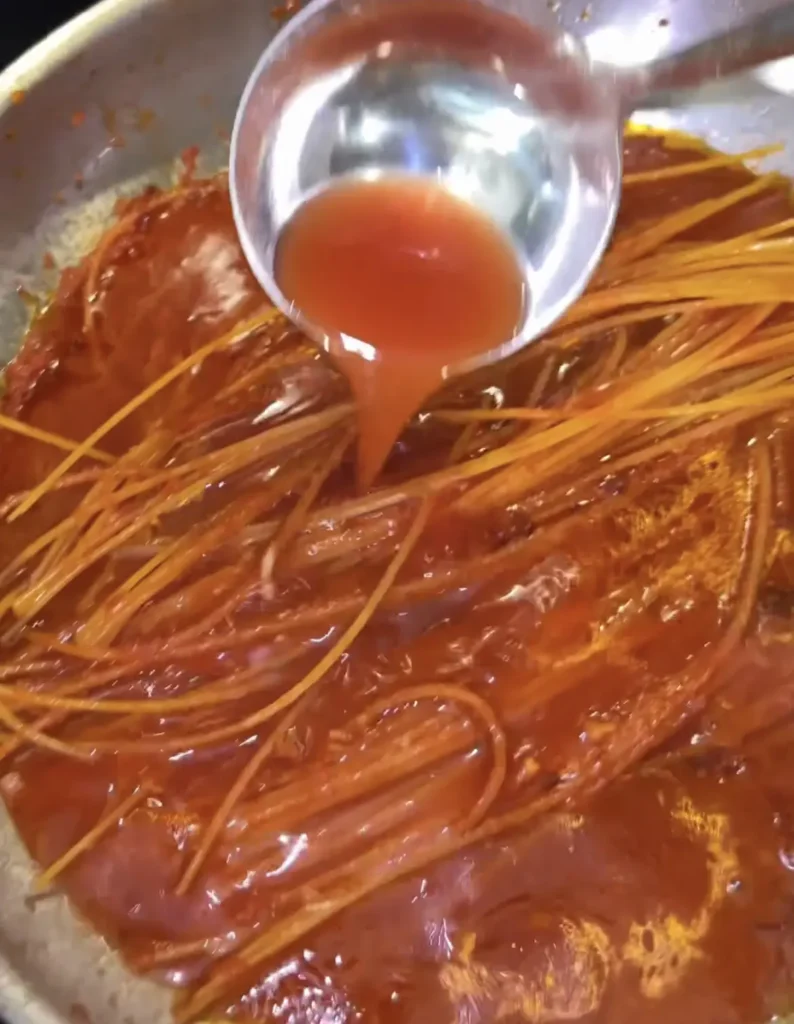 Adding more sauce to the spaghetti – Spaghetti all'Assassina
