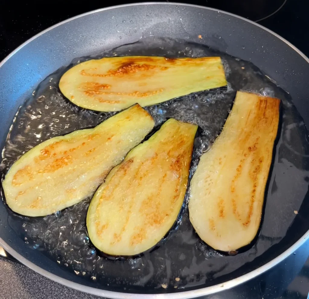 Eggplants getting fried in hot oil until they turn golden