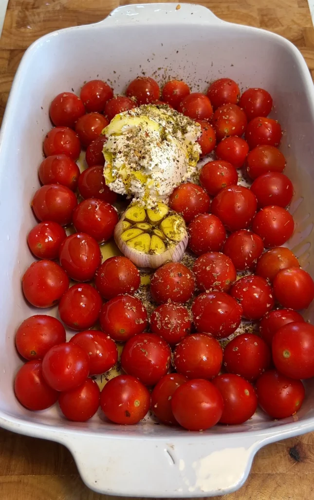 Roasted cherry tomatoes and garlic with feta in a baking dish.